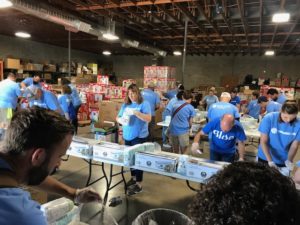 Several rows of volunteers sorts through diaper boxes.